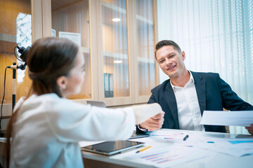 Fototapeta premium Caucasian businessman checking hands with young attractive businesswoman after finished business deals in office. Business and success concept