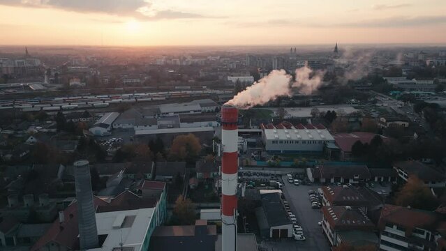 Aerial drone footage of an Industrial Chimney, smoke emission, flying near the pollutant in the air, burning gas for heat
