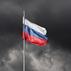 The tricolor flag of Russia white blue red on a flagpole against the background of dark storm clouds as a war close-up