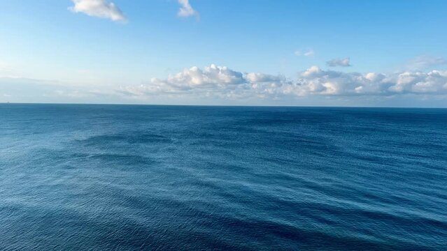 Beautiful view of the horizon of the blue sea, the Black Sea, the sky with white clear clouds. Small waves on the calm surface of the water. High quality FullHD footage