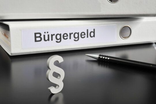 Hamburg, Germany - November 20, 2022: A paragraph sign in front of an office folder titled Bürgergeld the new system for financial support for unemployment in Germany