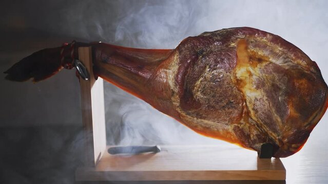 Jamon on a wooden stand in smoke.
