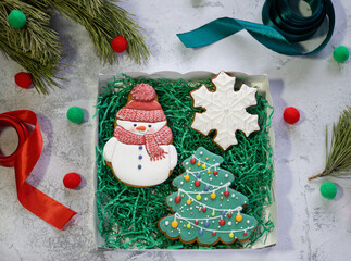 Gingerbreads in the form of snowman, Christmas tree and snowflake in gift box next to pine branch and ribbons. Christmas and New Year background. Preparing of Christmas gifts. Winter holidays concept