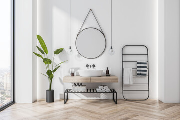 Naklejka na ściany i meble Front view on stylish sunlit bathroom with eco decoration, wooden sink cabinet and floor, round mirror on white wall background, city view from panoramic window and black towel holder. 3D rendering