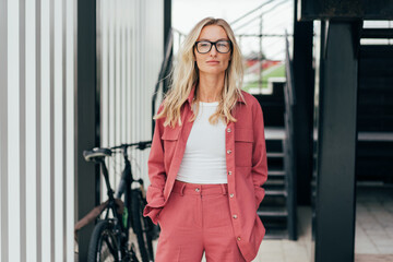 Fototapeta na wymiar Portrait of an elegant blonde confident woman in glasses standing and looking at the camera