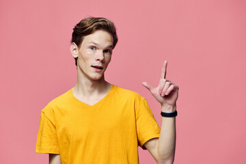 a guy in a yellow T-shirt on a pink background posing gesturing with his fingers