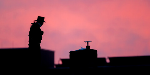 Fototapeta na wymiar Silhouette eines Kaminkehreres vor rotem Abendhimmel