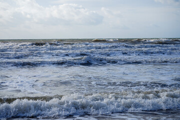 Waves crashing in the ocean with a cloudy sky
