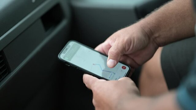 Closeup of a man using GPS and Google maps navigation in his phone in a car