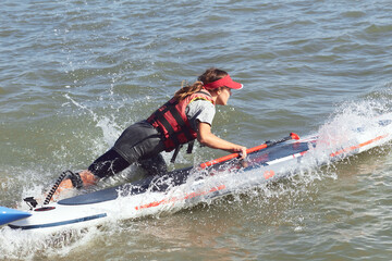Woman starts on SUP from the shore. River beach start on rowing competitions on SUP (stand up paddle boarding)