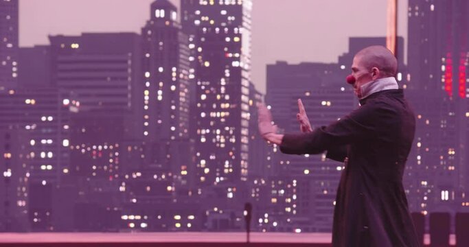 Clown funny mime behind an invisible glass box or wall. Entering the invisible door. Modern city downtown skyline and window lights at the night. 