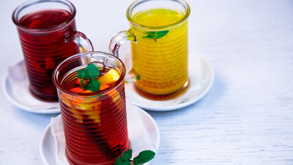 Tea with fruits, lemon and mint leaves. Tea with various fruits in transparent glass mugs.