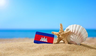 Fototapeta na wymiar Tropical beach with seashells and Cambodia flag. The concept of a paradise vacation on the beaches of Cambodia.
