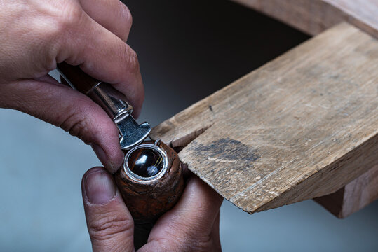 Jeweller setting a tiger iron stone into the bezel set on the silver pendant