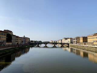 Obraz premium Firenze, Tuscany, Italy. Sunny day at Arno River, the Lungarno and the Ponte alla Carraia bridge, in a view from the Santa Trinità bridge. The neighborhood surrounding the Arno river