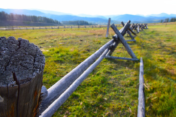 Multi-colored image of wooden fence on ranch with Colorado mountain range in the background