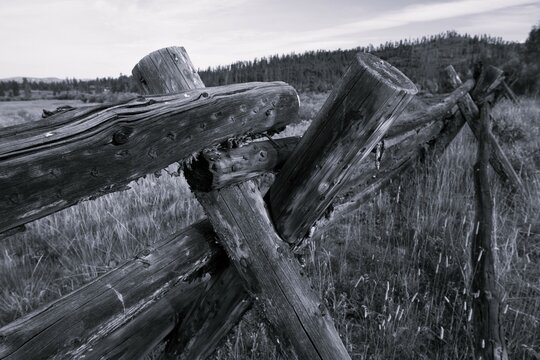 Black and white image of wooden fence on American ranch in Colorado mountains