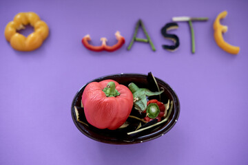 pieces of edible vegetables forming the word zero waste next to a black bowl with peppers
