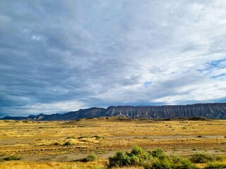 Dramatic view of mountain range with meadows in front and cloudscape in the sky