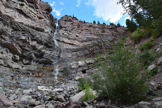 Horizontal color image of waterfall from rocky cliff in Colorado mountain forest