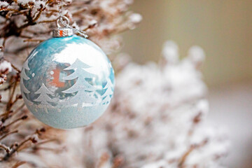 blue Christmas ball hangs on a snow-covered Christmas tree. Festive background.