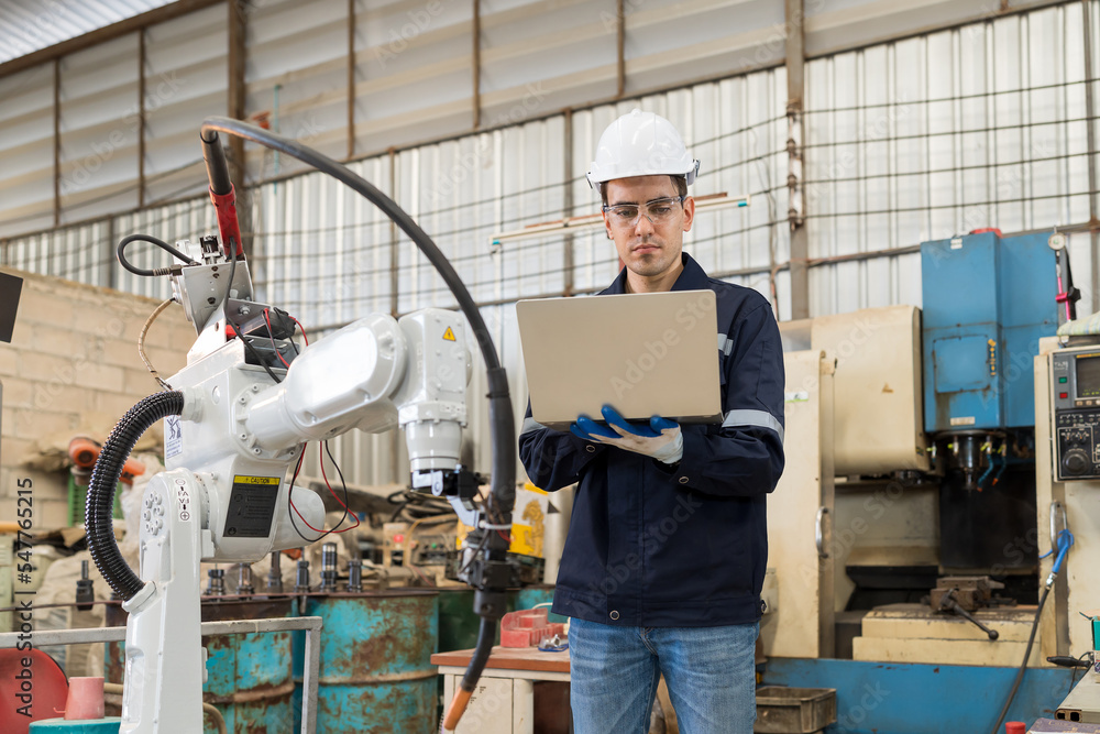 Aufkleber Male engineers worker using laptop computer working with adept robot arm in workshop. Male technician maintenance automatic robot arm system welding with laptop computer in factory