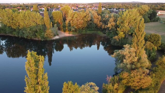 Aerial drone view of Lake Lohnder Kiesteich in Germany surrounded by yellow trees