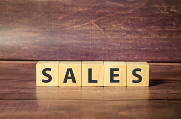 sales word made with wooden blocks and brown background