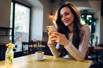 Portrait of beautiful young woman using smartphone in a cafe