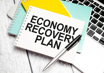 ECONOMY RECOVERY PLAN words on paper notebook with pen