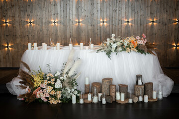 Romantic boho main table. Wedding decor with dried flowers floristry, stumps, and candles, boho style. Pampas grass