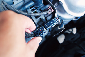 Technician inserting the alternator or generator plug of the car in the engine compartment,...