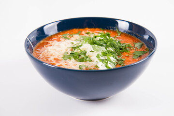 Italian tomato soup served with cream, mozzarella cheese and fresh parsley in a bowl, on a white backgound