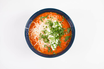 Italian tomato soup served with cream, mozzarella cheese and fresh parsley in a bowl, on a white backgound