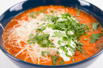 Italian tomato soup served with cream, mozzarella cheese and fresh parsley in a bowl, on a white backgound
