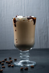 Coffee with cream and chocolate syrup in a mug with coffee beans.