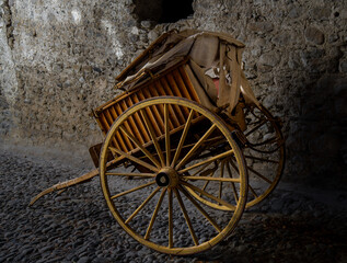 Fototapeta na wymiar Old wooden cart for agricultural work, well preserved, resting on a stone floor of a rural house.