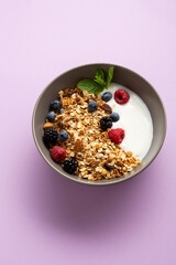 Breakfast granola with berry in bowl food yogurt on purple surface