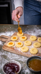 Weihnachten Plätzchen backen, Weihnachtsbäckerei, frisch gebackene Plätzchen mit verschiedenen Marmeladen füllen, Spitzbuben Plätzchen