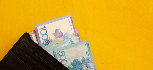 Horizontal banner with cash paper banknotes of Kazakhstan on yellow textile background. Money fell out of wallet. Concept of paying for purchases, repaying loan. Kazakh tenge. Bill. Currency exchange