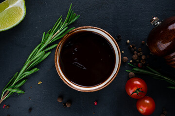 Soy sauce in a bowl with rosemary, tomatoes, lime and spices.