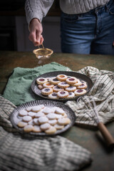 Weihnachten Plätzchen backen, Weihnachtsbäckerei, frisch gebackene Plätzchen mit Puderzucker bestreuen