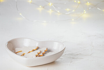 Gingerbread christmas trees in a faience white bowl in the form of heart on a concrete surface, close-up view. Christmas celebration concept with space for text