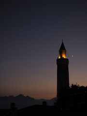 Night silhouette of the historical Yivli Minaret mosque. Crescent sky and minaret.