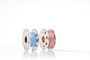 spools of blue and pink thread on a white background