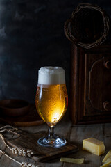 Glass of beer and sliced cheese on rustic table