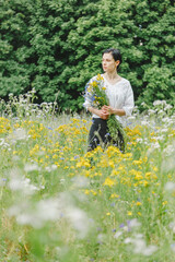 Beautiful girl among the summer field with wildflowers