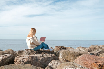 Naklejka premium Remote work.Girl freelancer works remotely on the sea shore. workation, remote work,WFVH,Van Life vibes work from vacation home,work travel,remotely work.Travelling.Work from vacation remotely