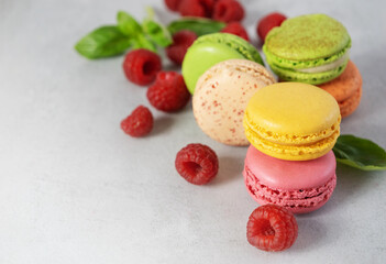Colored Fruity Macaroons, macarons with Raspberries on a gray background with copy space. Confectionery with berries.