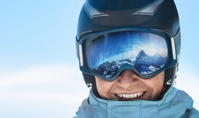  Man on the background blue sky. Wearing ski glasses. Winter Sports. A mountain range reflected in the ski mask.